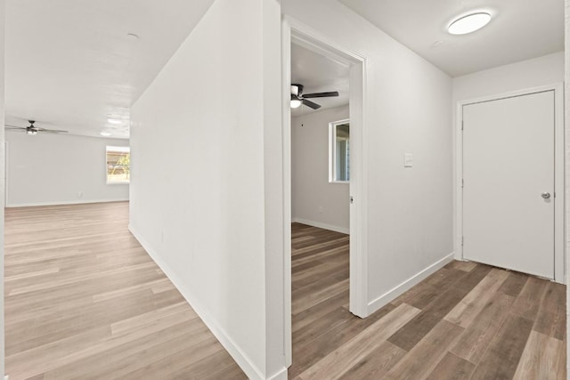 corridor featuring baseboards and light wood-style floors