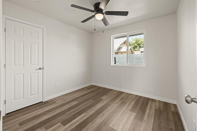 empty room with ceiling fan, baseboards, and wood finished floors