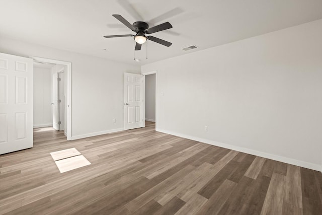 empty room with light wood finished floors, a ceiling fan, visible vents, and baseboards