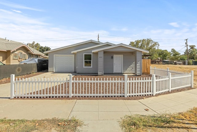 view of front facade featuring concrete driveway, a fenced front yard, and an attached garage