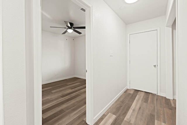 hall featuring visible vents, baseboards, and wood finished floors