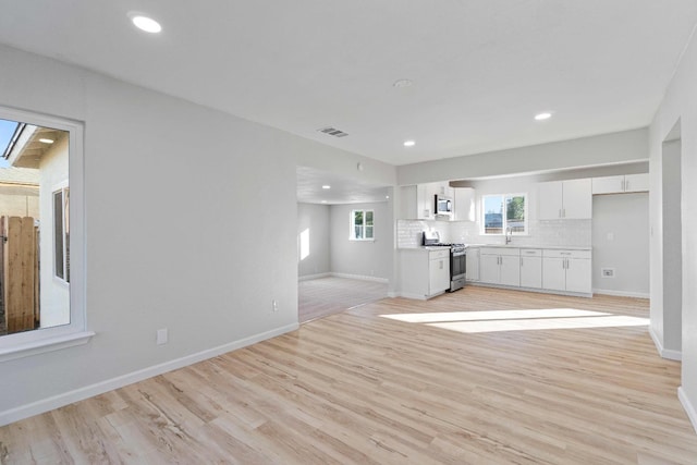 unfurnished living room featuring light wood-type flooring and sink