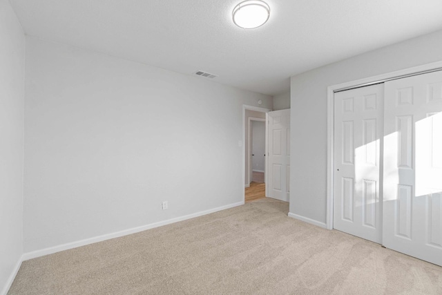 unfurnished bedroom with light carpet and a closet