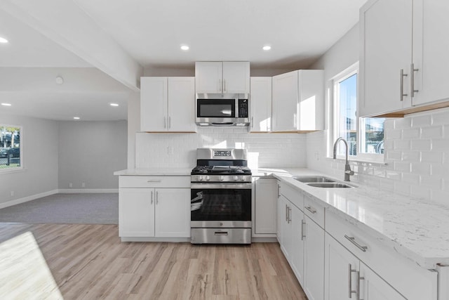 kitchen with light wood-type flooring, appliances with stainless steel finishes, sink, and white cabinetry