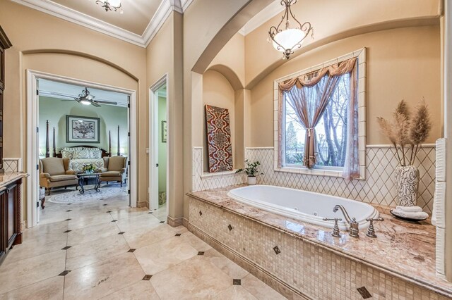 bathroom with ceiling fan, vanity, a relaxing tiled tub, and ornamental molding