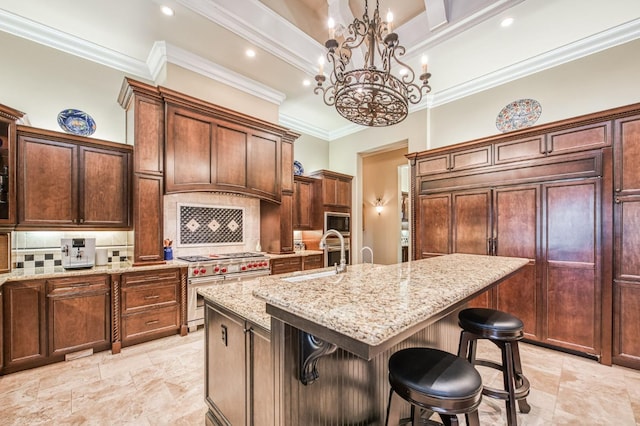 kitchen featuring pendant lighting, a center island with sink, decorative backsplash, sink, and built in appliances