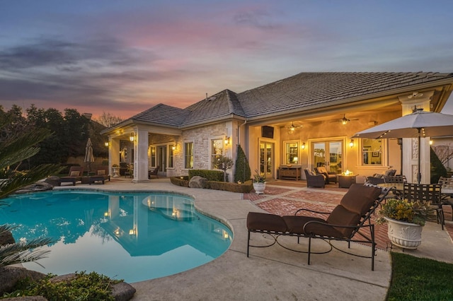 pool at dusk featuring ceiling fan, french doors, an outdoor hangout area, and a patio