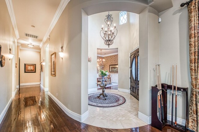 corridor with a chandelier, crown molding, and wood-type flooring