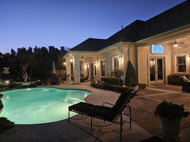 pool at dusk with ceiling fan, a patio, and an in ground hot tub