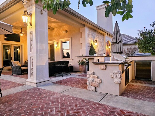 patio terrace at dusk featuring exterior kitchen and area for grilling