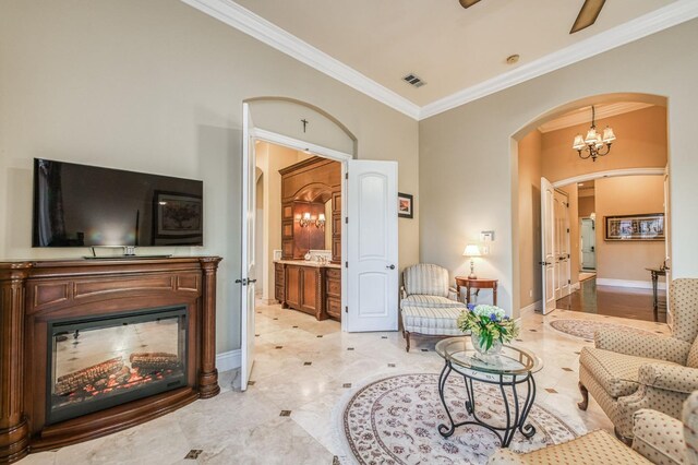 living room featuring crown molding and ceiling fan with notable chandelier