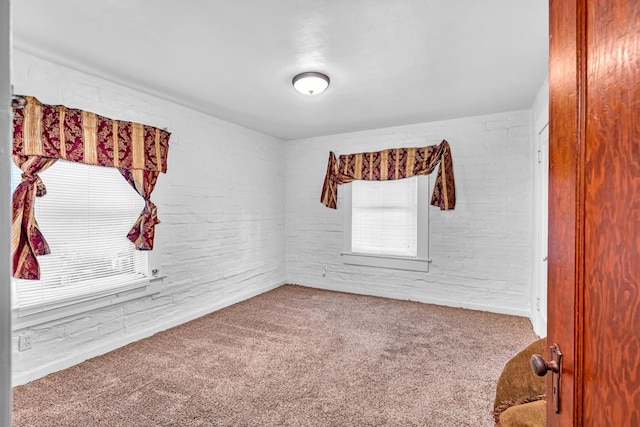 spare room featuring carpet and brick wall