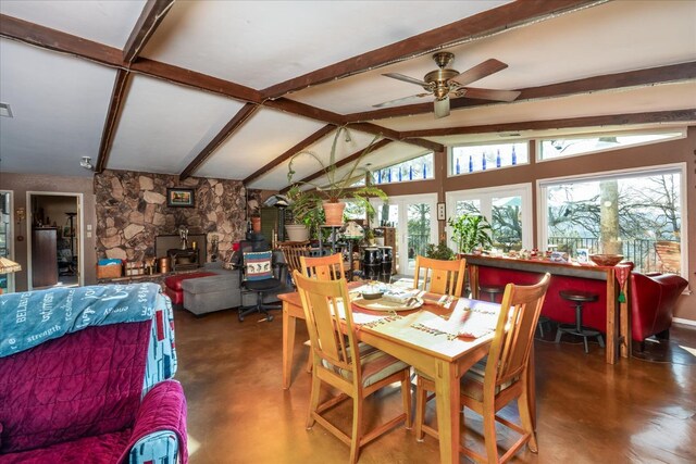 dining room with vaulted ceiling with beams, ceiling fan, and a wood stove