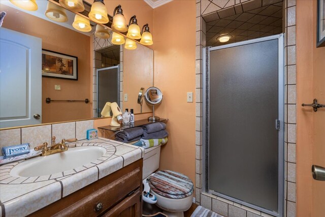 bathroom featuring vanity, decorative backsplash, a shower with door, and toilet