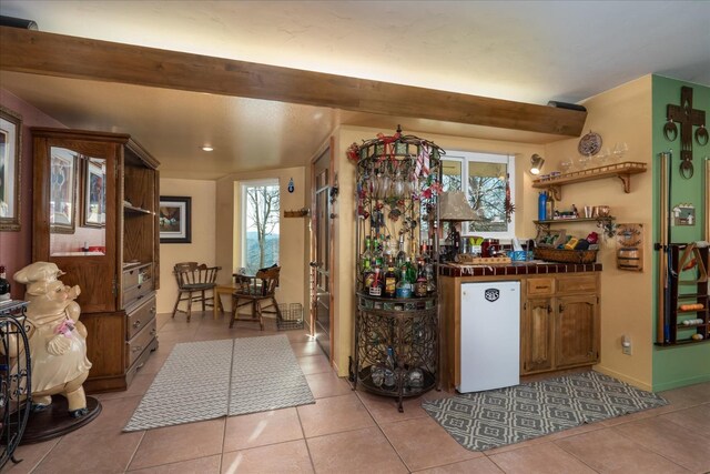 bar with fridge, tile counters, and light tile patterned floors