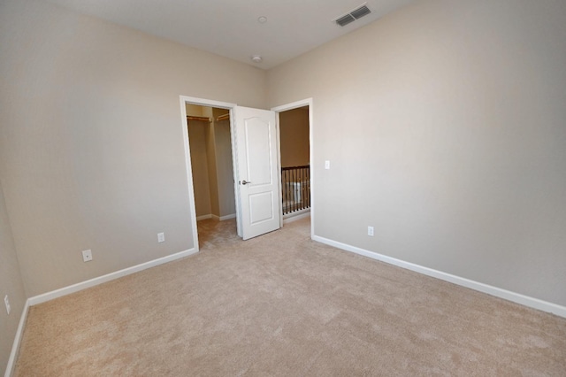 unfurnished bedroom featuring light carpet, a closet, and a spacious closet