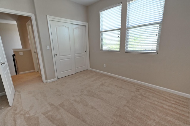 unfurnished bedroom with light colored carpet and a closet