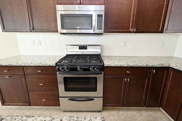 kitchen with light stone counters, decorative backsplash, and stainless steel appliances