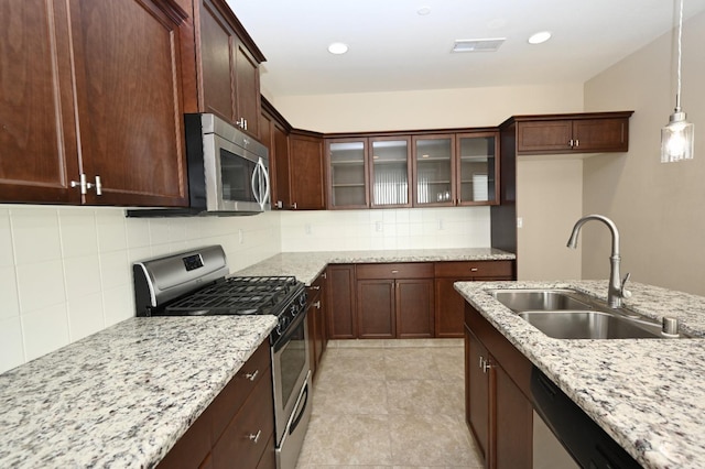 kitchen featuring decorative backsplash, sink, hanging light fixtures, appliances with stainless steel finishes, and light stone counters