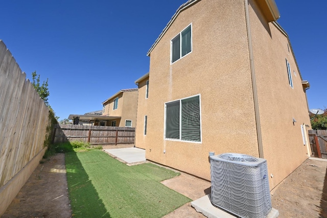 rear view of house featuring a lawn, cooling unit, and a patio area