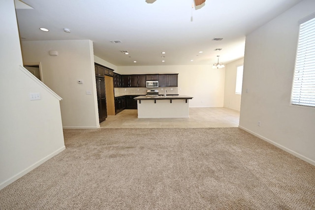 unfurnished living room with light colored carpet and ceiling fan with notable chandelier