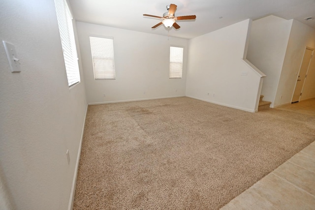 unfurnished living room featuring ceiling fan, a wealth of natural light, and light colored carpet