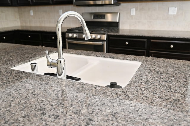 room details featuring sink, backsplash, stone counters, and stainless steel range with gas stovetop