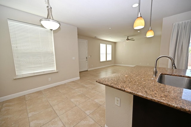 kitchen featuring light tile patterned floors, ceiling fan, decorative light fixtures, light stone countertops, and sink