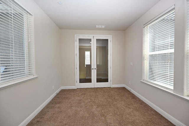 empty room with plenty of natural light, carpet, and french doors