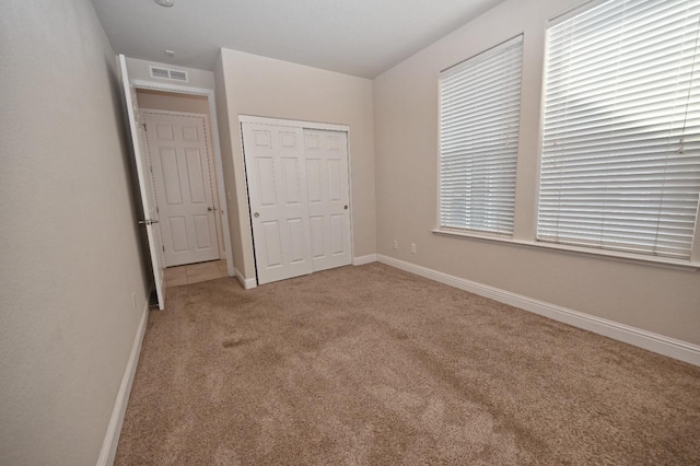 unfurnished bedroom with light colored carpet and a closet