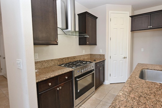 kitchen featuring gas range, light stone countertops, light tile patterned floors, and wall chimney exhaust hood