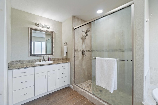 bathroom featuring a shower with shower door and vanity