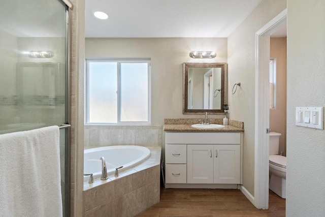 full bathroom with toilet, shower with separate bathtub, hardwood / wood-style floors, and vanity