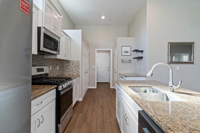 kitchen featuring light stone counters, sink, white cabinetry, and appliances with stainless steel finishes