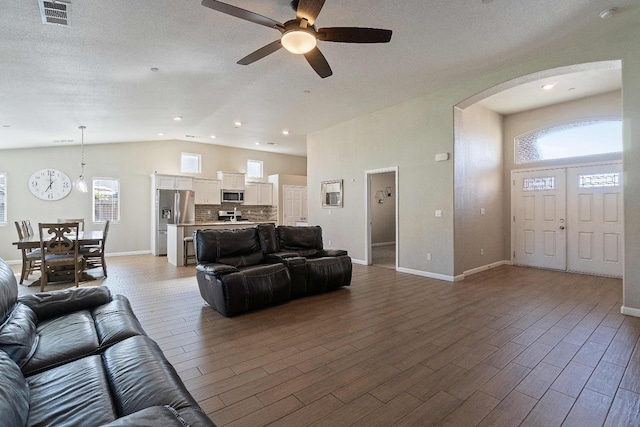 living room with ceiling fan, lofted ceiling, and plenty of natural light