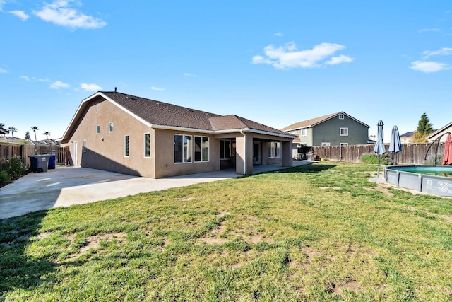 rear view of property with a lawn, a patio area, and a fenced in pool