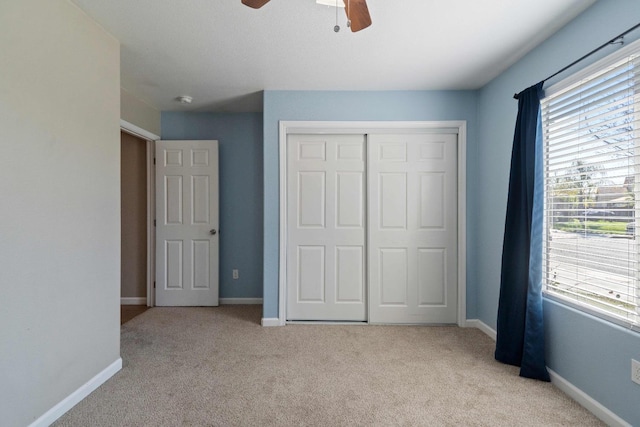 unfurnished bedroom with ceiling fan, a closet, and light carpet