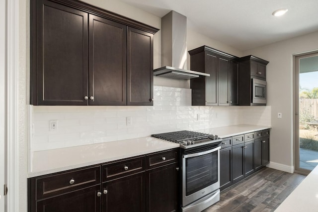 kitchen with appliances with stainless steel finishes, wall chimney exhaust hood, dark hardwood / wood-style flooring, and dark brown cabinetry