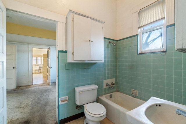 full bathroom featuring sink, tile walls, toilet, and tiled shower / bath