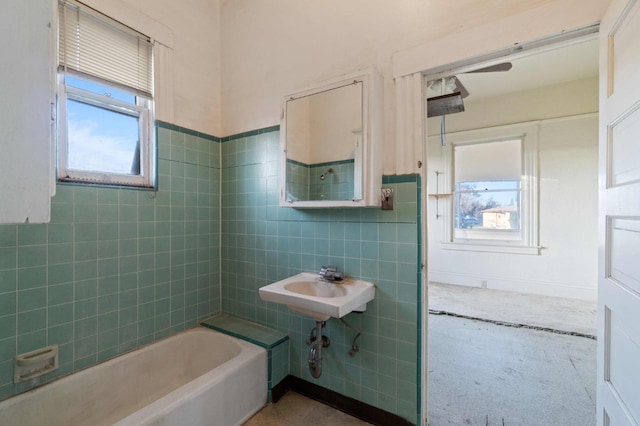 bathroom featuring shower / bathing tub combination, tile walls, plenty of natural light, and sink