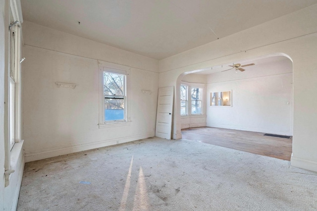 carpeted empty room with ceiling fan and a wealth of natural light