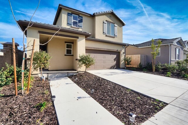 traditional-style house featuring driveway, an attached garage, fence, and stucco siding