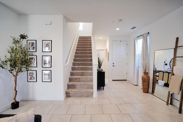 entryway with light tile patterned floors, baseboards, visible vents, stairs, and recessed lighting