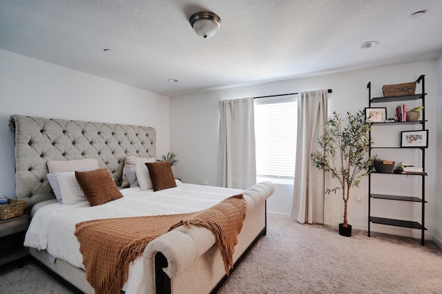 bedroom with light carpet, a textured ceiling, and baseboards