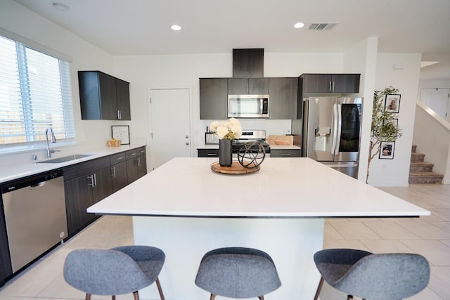 kitchen featuring visible vents, a kitchen breakfast bar, light countertops, stainless steel appliances, and a sink