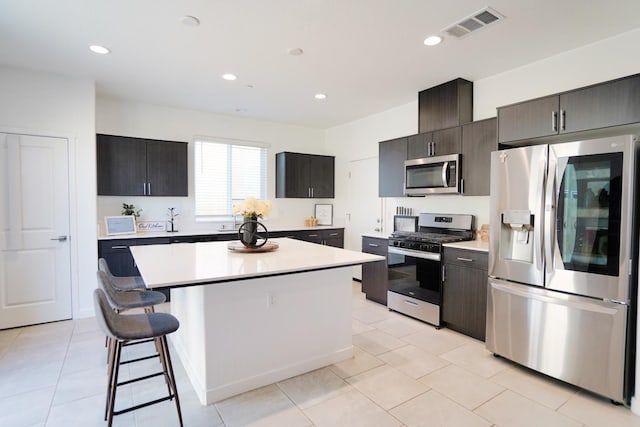 kitchen featuring light tile patterned floors, a kitchen bar, stainless steel appliances, and a center island