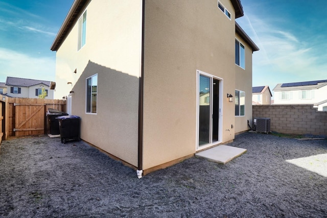 back of house with cooling unit, fence, a residential view, and stucco siding