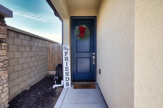 property entrance featuring fence and stucco siding