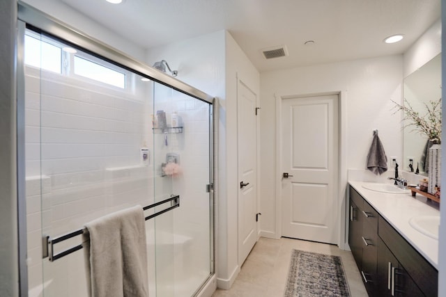 bathroom featuring double vanity, a stall shower, a sink, and visible vents