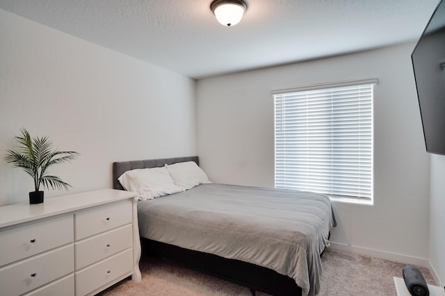 bedroom featuring light carpet and baseboards